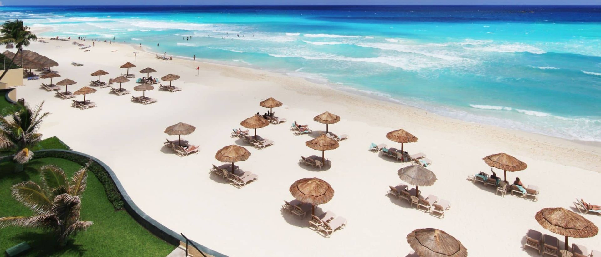 An aerial view of a beach with lounge chairs and umbrellas.