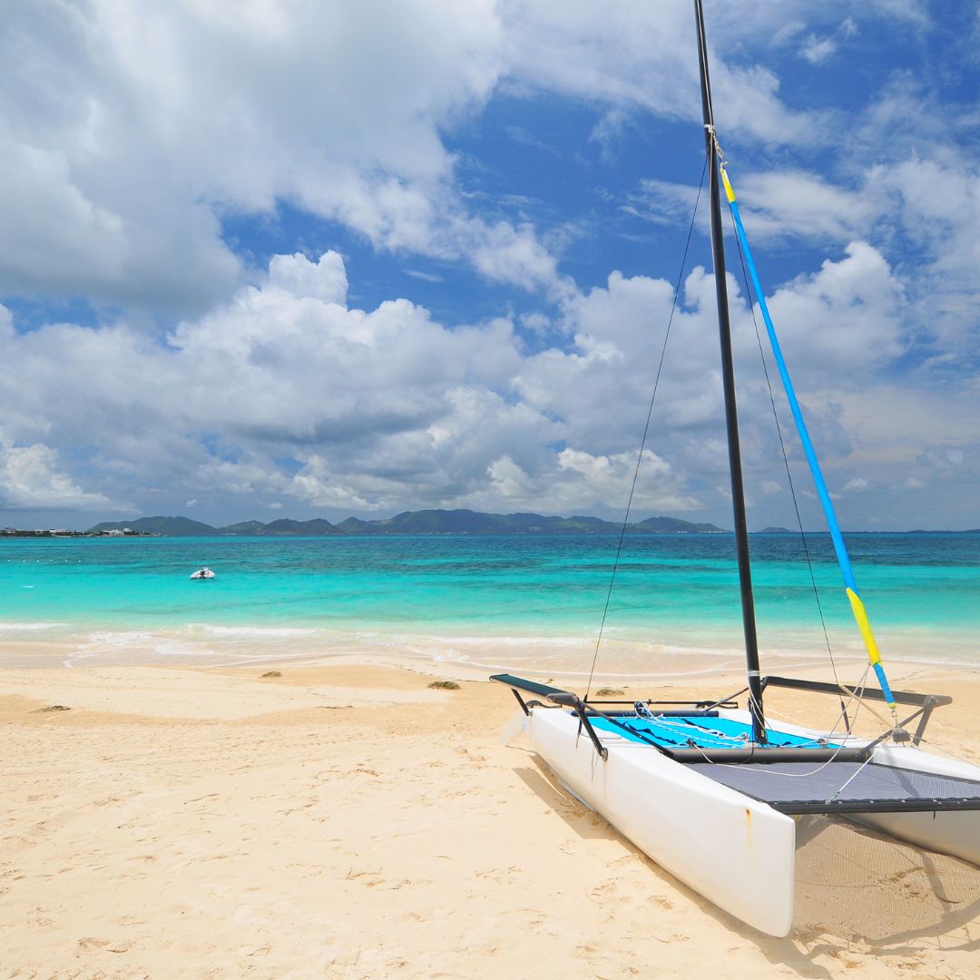 Three lounge chairs under thatched umbrellas on a sandy beach.