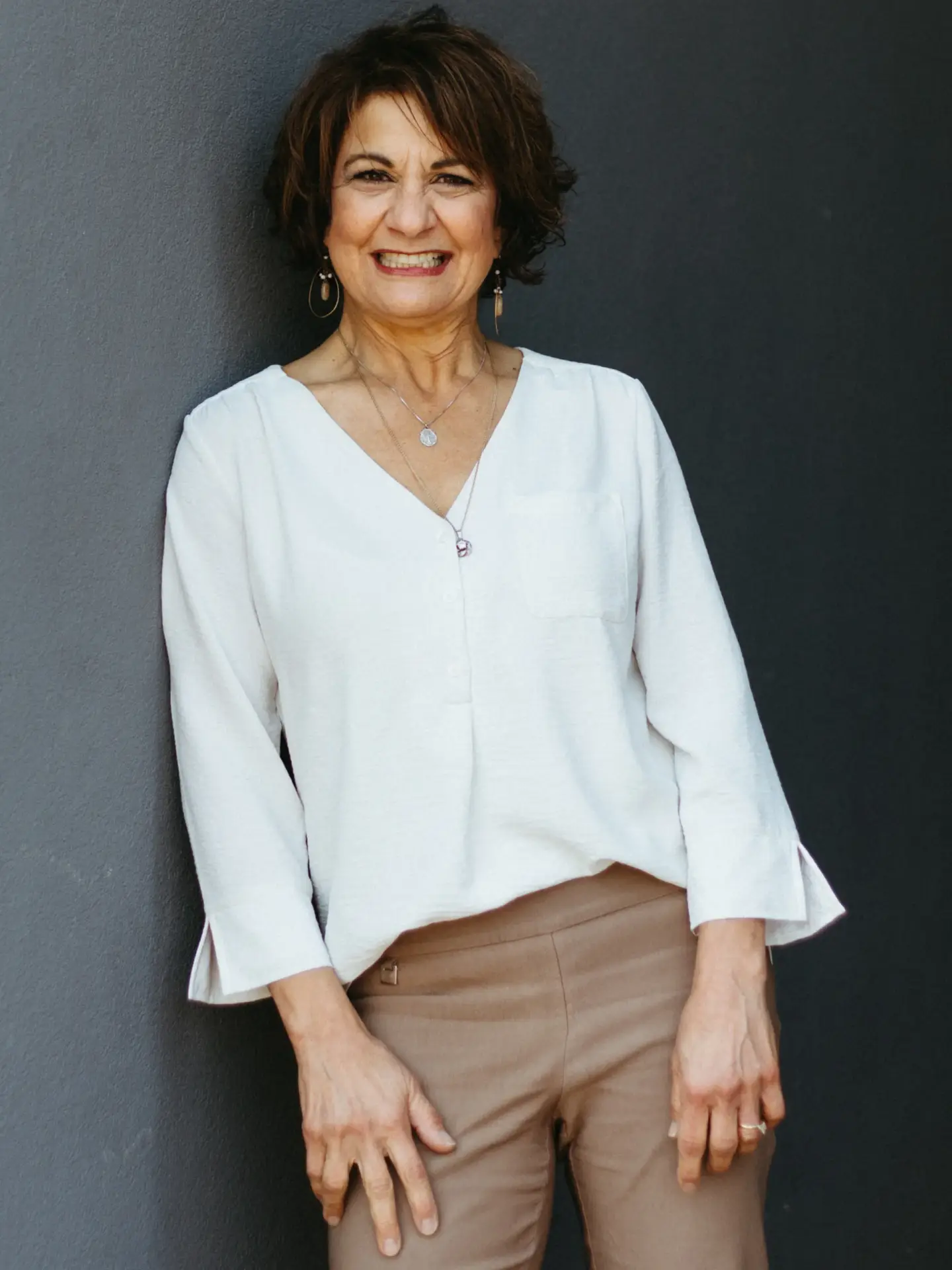 a woman leaning against a wall with her hands on her hips.